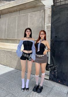 Two women in fashionable outfits and glasses standing on a street