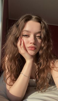 Woman with long wavy brown hair in soft golden hour lighting indoors