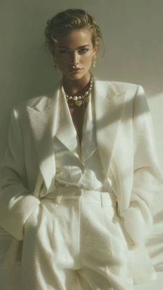 Woman in a white suit with a pearl necklace and updo hairstyle
