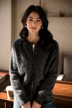 Woman with long dark hair wearing a cardigan and jeans indoors