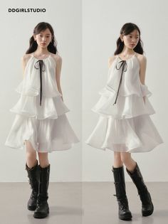 Young woman in a white tiered dress and black boots posing indoors