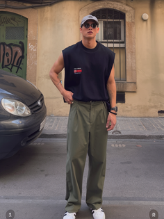 Man in a black sleeveless shirt and olive baggy pants on a street