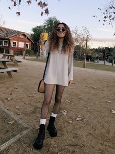 Woman with curly hair and sunglasses holding a cup outdoors