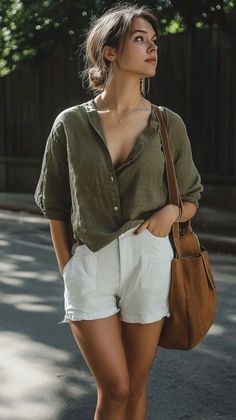 Woman in a green shirt and white shorts with a brown bag outdoors