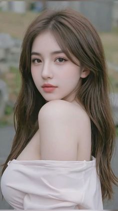 Woman with long brown hair wearing an off-shoulder top outdoors