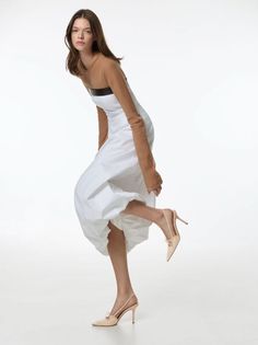 Woman in a white dress and high heels posing in a studio
