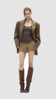 Woman in an oversized blazer, mini skirt, and knee-high boots posing in a studio