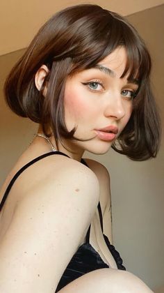 Woman with short brown hair and blue eyes wearing a black top