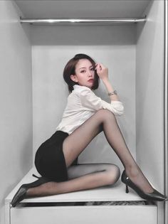 Woman in a white shirt and black skirt with pantyhose posing indoors
