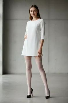 Woman in a white dress and white stockings posing indoors