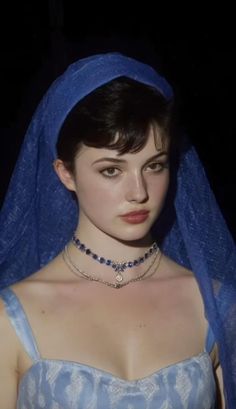 Woman with a blue veil and dress, wearing a blue gemstone necklace