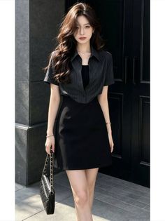 Woman in a black short-sleeve shirt and mini skirt holding a black handbag