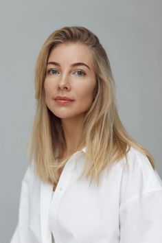 Woman with blonde hair and blue eyes wearing a white shirt, looking at the camera