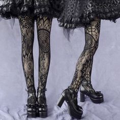 Two pairs of legs wearing black lace tights and platform shoes