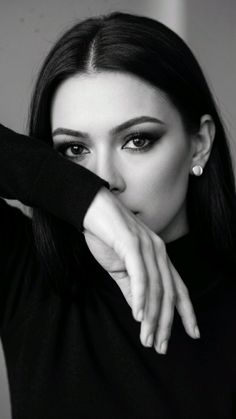 Woman with dark hair and dramatic eye makeup covering her mouth with her arm
