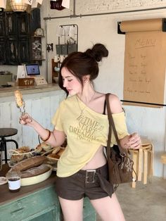 Woman with a bun hairstyle wearing an off-shoulder top and shorts in a bakery