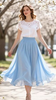 Woman in a white blouse and blue skirt walking outdoors among cherry blossoms