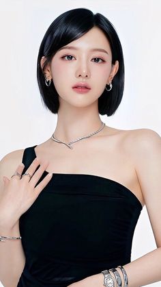 Woman with short black hair wearing a one-shoulder top and jewelry