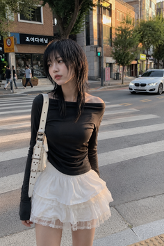 Woman with black hair wearing an off-shoulder top and white ruffle skirt on a street