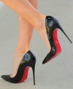 Pair of black high heels with red soles on a person's feet