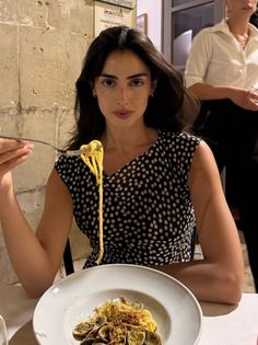 Woman in a polka dot dress eating pasta at a restaurant