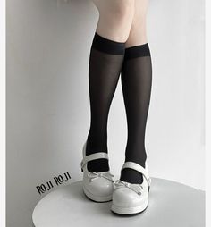 Legs wearing black knee-high stockings and white platform Mary Jane shoes with bows