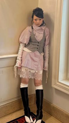 Person in a plaid vest, striped shirt, and lace-trimmed skirt with knee-high boots