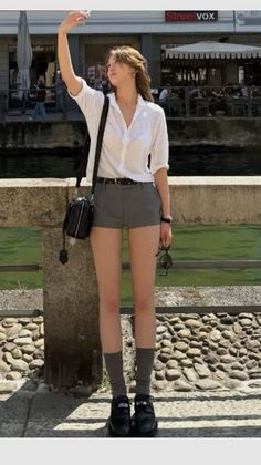 Woman in a white shirt and gray shorts taking a selfie outdoors