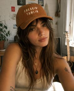 Woman in a baseball cap and tank top indoors with soft lighting