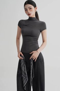 Woman in a dark gray top and pinstripe pants holding a patterned scarf