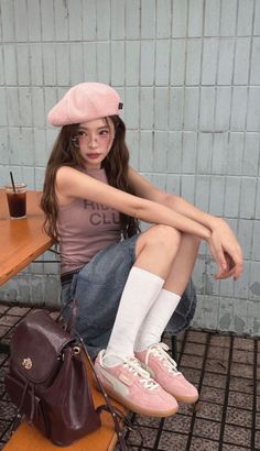 Woman in a pink beret, denim skirt, and pink sneakers sitting outdoors