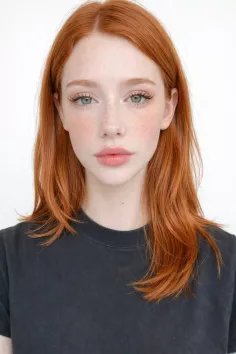 Woman with red hair and freckles wearing a dark t-shirt against a white background
