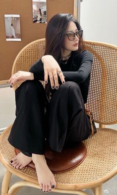 Woman with long dark hair and sunglasses sitting on a wicker chair