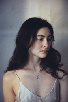 Woman with long dark hair wearing a spaghetti strap top and silver necklace