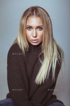 Young woman with long blonde hair and blue eyes wearing a dark turtleneck sweater