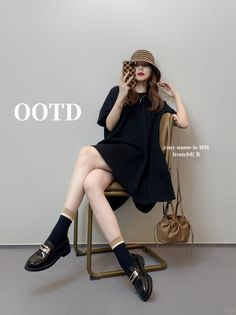 Woman in a black dress and bucket hat sitting on a chair indoors