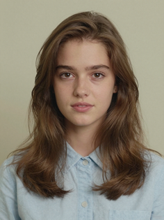 Young woman with long brown hair wearing a light blue collared shirt