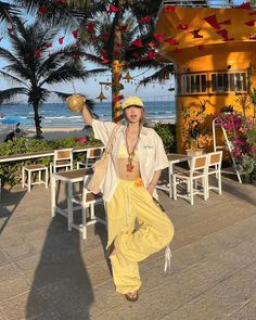 Woman in a yellow outfit holding a coconut drink on a sunny beach patio