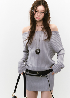 Woman in a light gray off-shoulder dress with a heart necklace and glasses