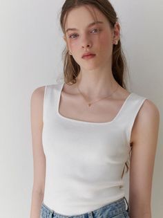 Woman with long hair wearing a white tank top and blue jeans