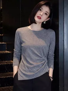 Woman with short hair and red lipstick wearing a gray top and black pants