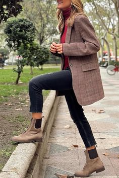 Woman in a plaid blazer and black jeans posing outdoors