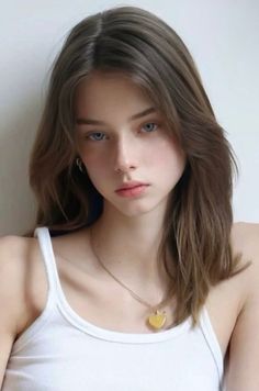Young woman with long brown hair and blue eyes wearing a white tank top