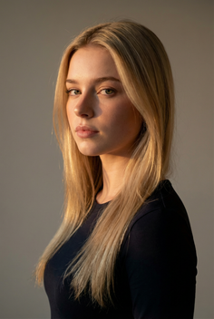 Blonde woman with long hair in a black shirt, lit by soft warm light