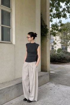 Woman with a bun and glasses wearing a sleeveless top and wide leg pants outdoors