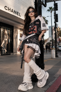 Woman in a jersey shirt, mini skirt, and leg warmers on a city street