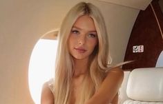 Woman with long blonde hair and blue eyes inside a private jet