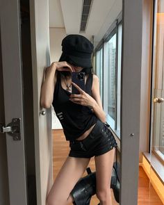 Woman in a black tank top and shorts taking a mirror selfie