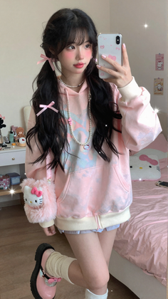 Woman with twin tails and a pink hoodie taking a mirror selfie in a bedroom
