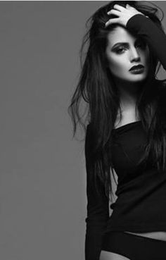 Woman with long dark hair and dark lipstick in a black top and underwear